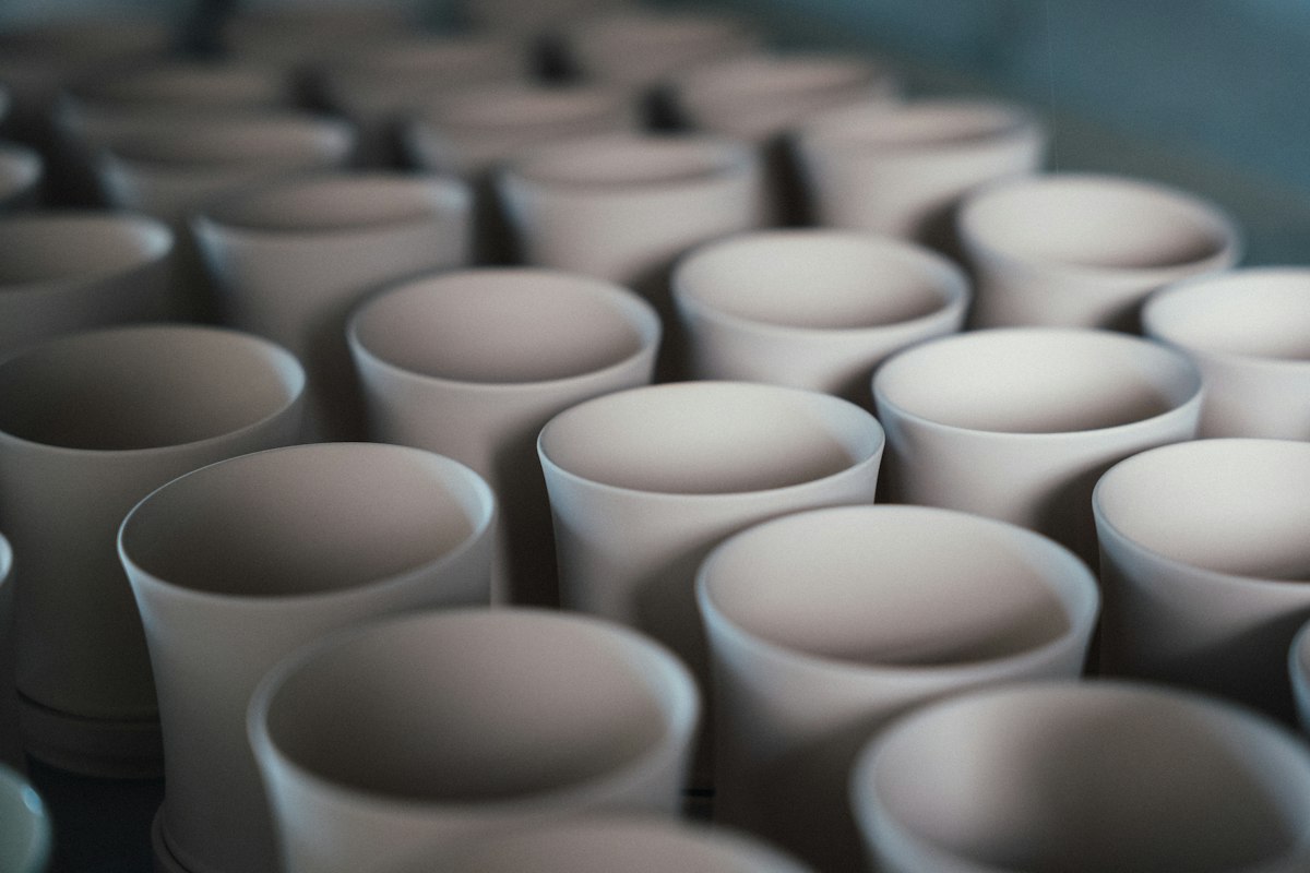 Des tasses en céramique blanche alignées avant cuisson