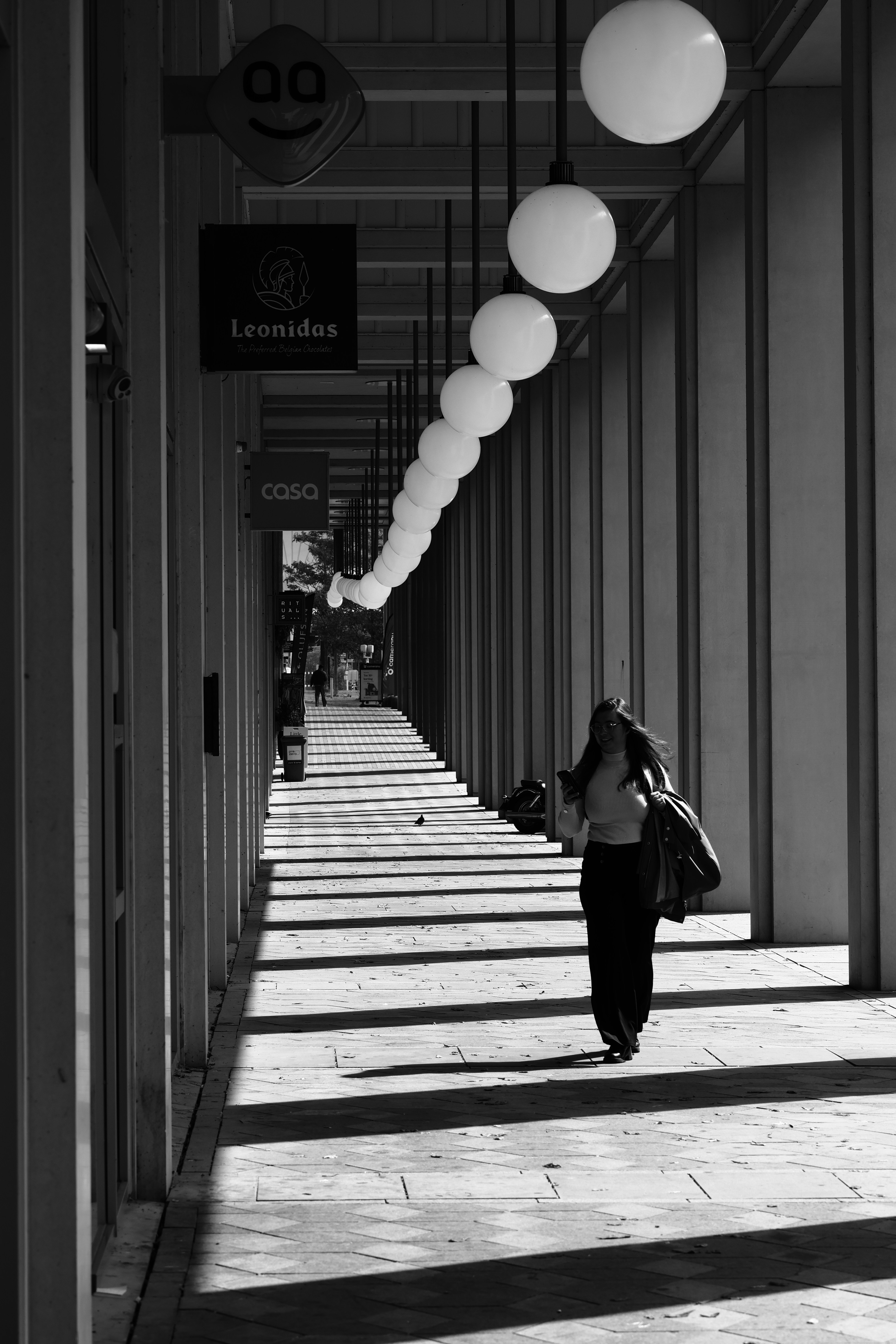 Mulher caminhando por um fliperama iluminado pelo sol com sombras