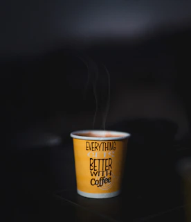 Steaming cup of coffee with text on yellow paper cup