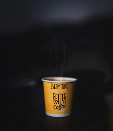Steaming cup of coffee with text on yellow paper cup