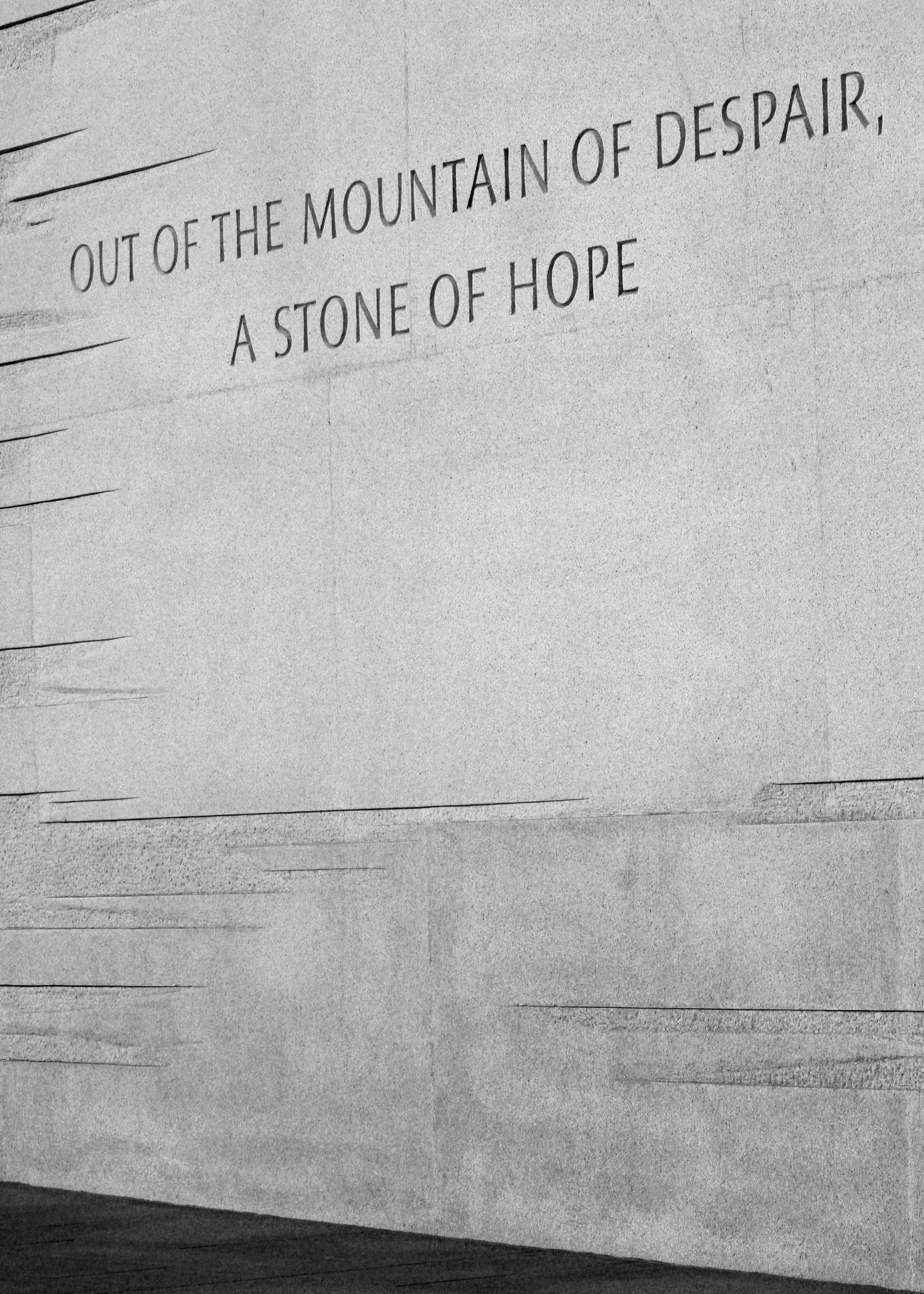Words inscribed on a textured stone wall.