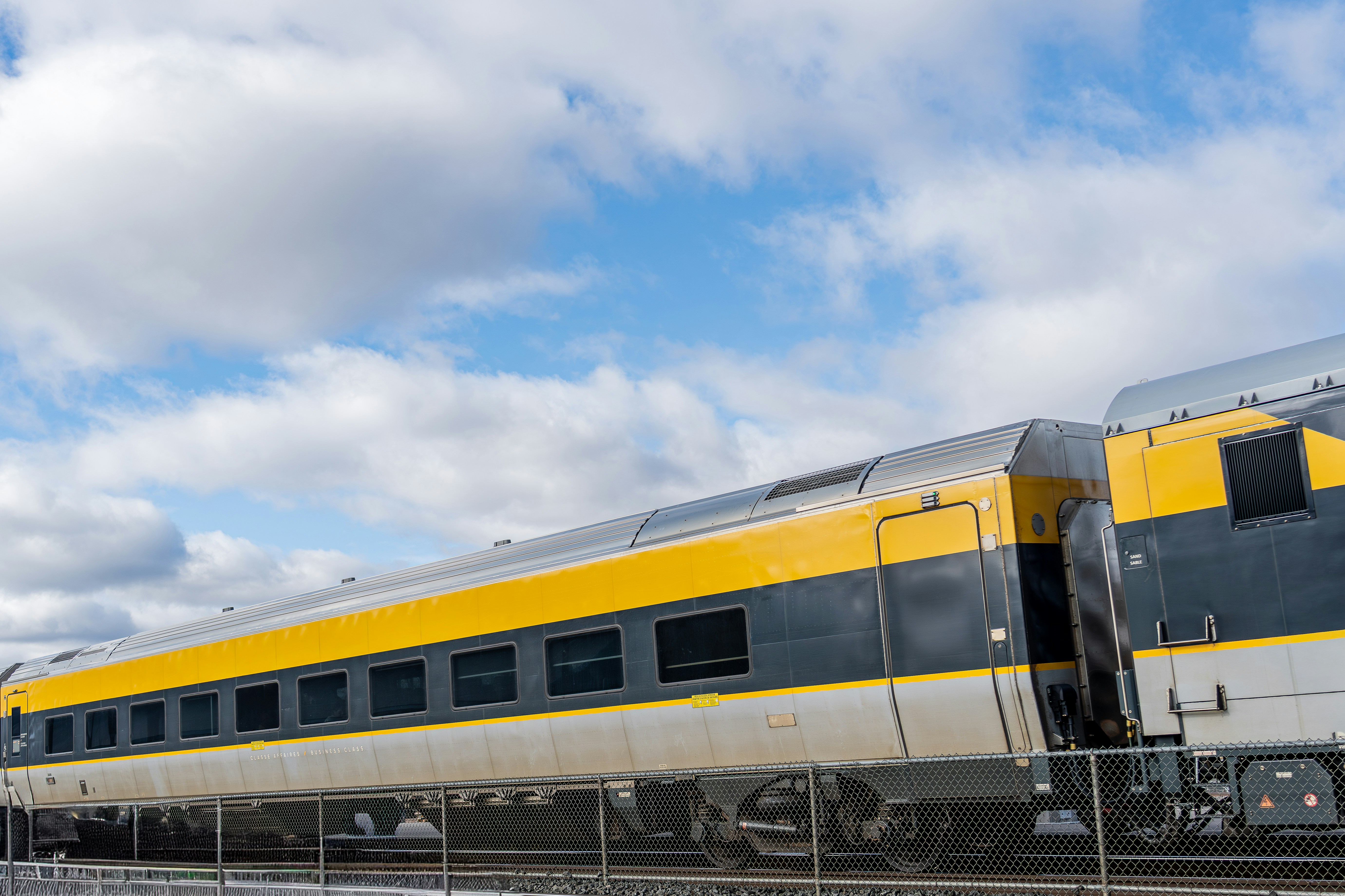Yellow and black train cars under a cloudy sky