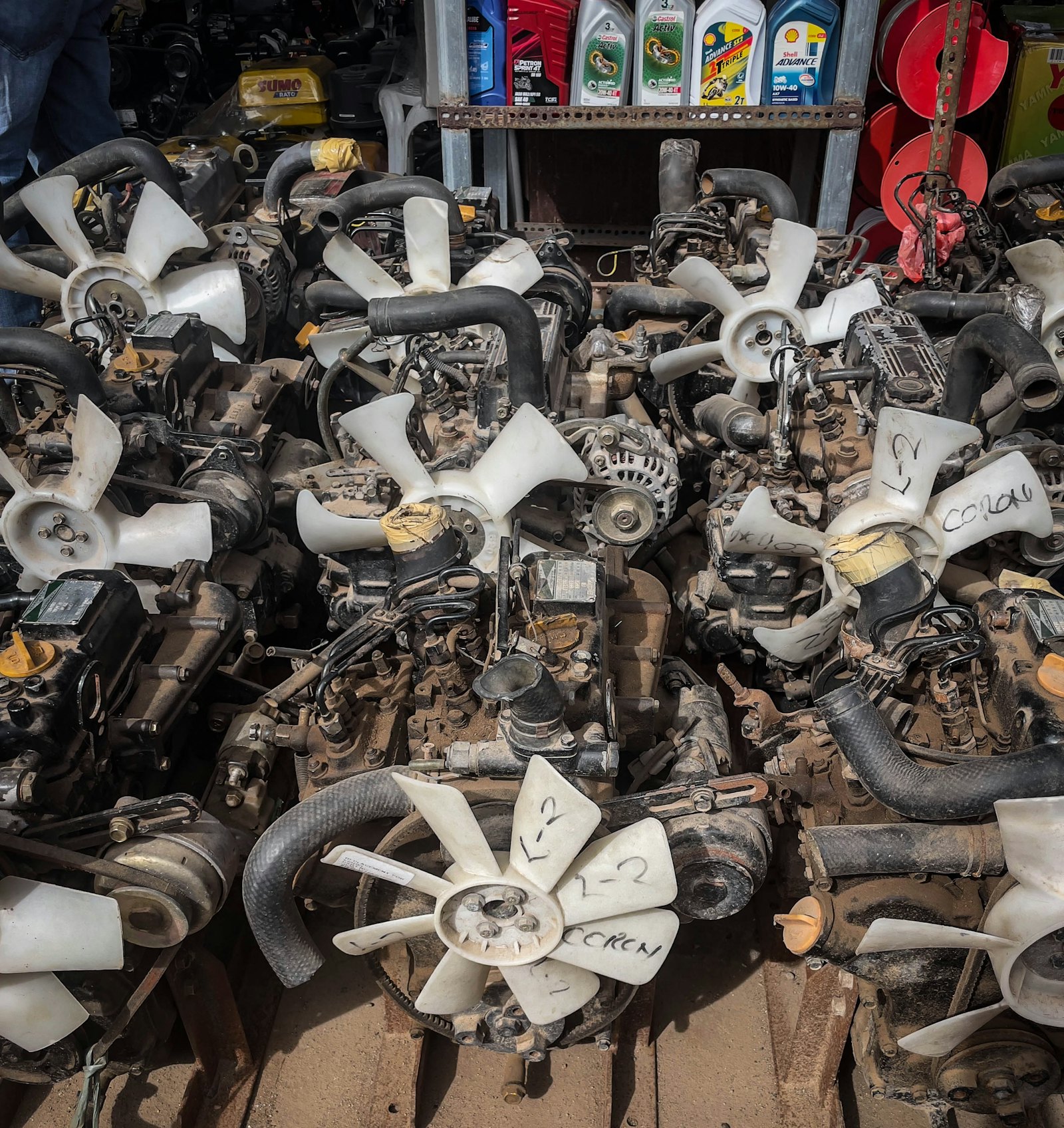 A pile of automotive engine parts, fan blades and components on shelving