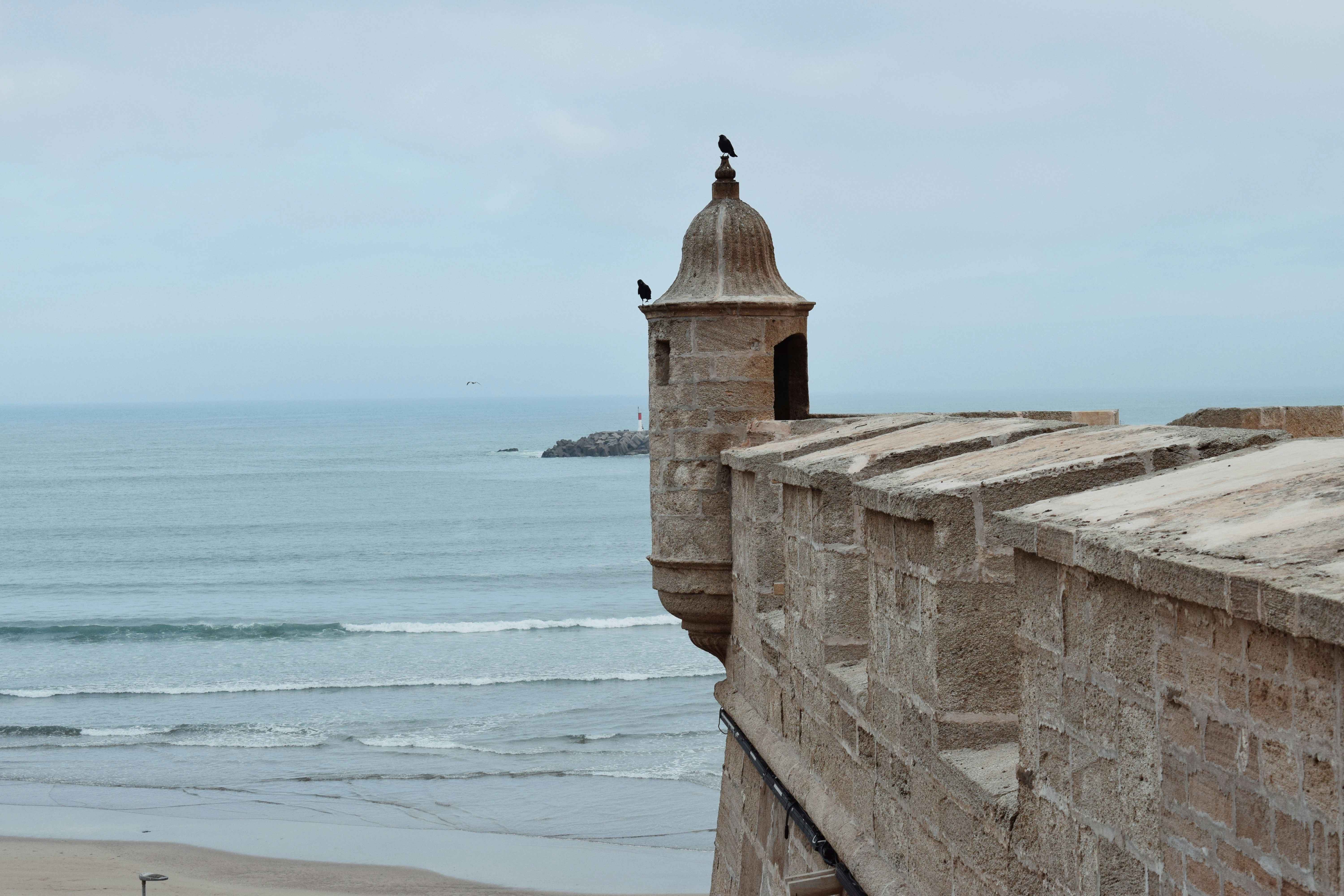 Stone fortress wall overlooking the ocean under a cloudy sky