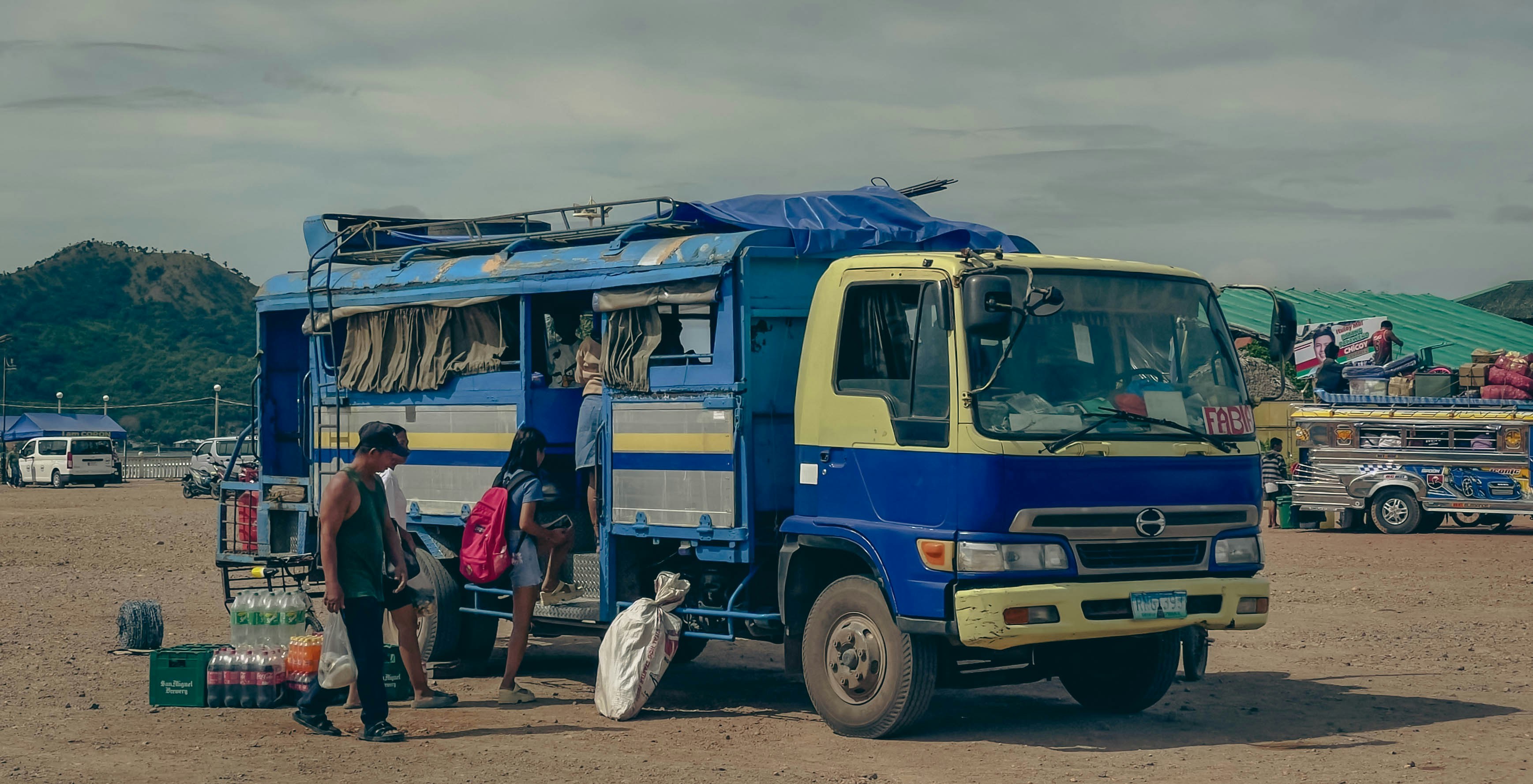 A blue and yellow truck with people boarding