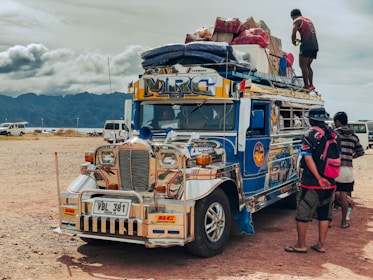 A colorful jeepney overloaded with luggage and people.