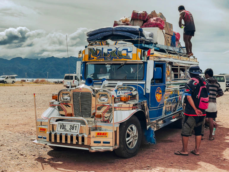 A colorful jeepney overloaded with luggage and people.