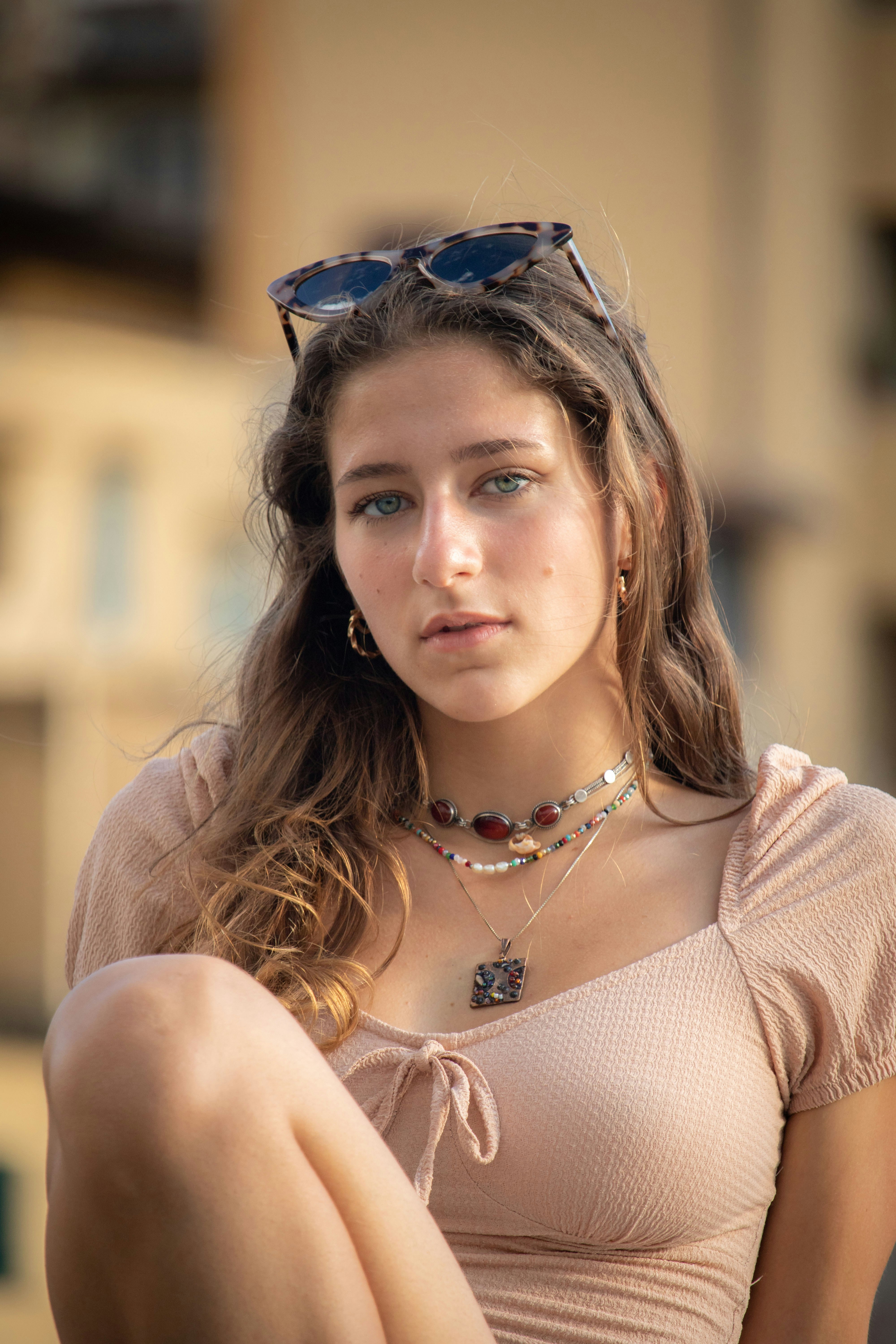 Young woman wearing sunglasses on her head and necklaces.