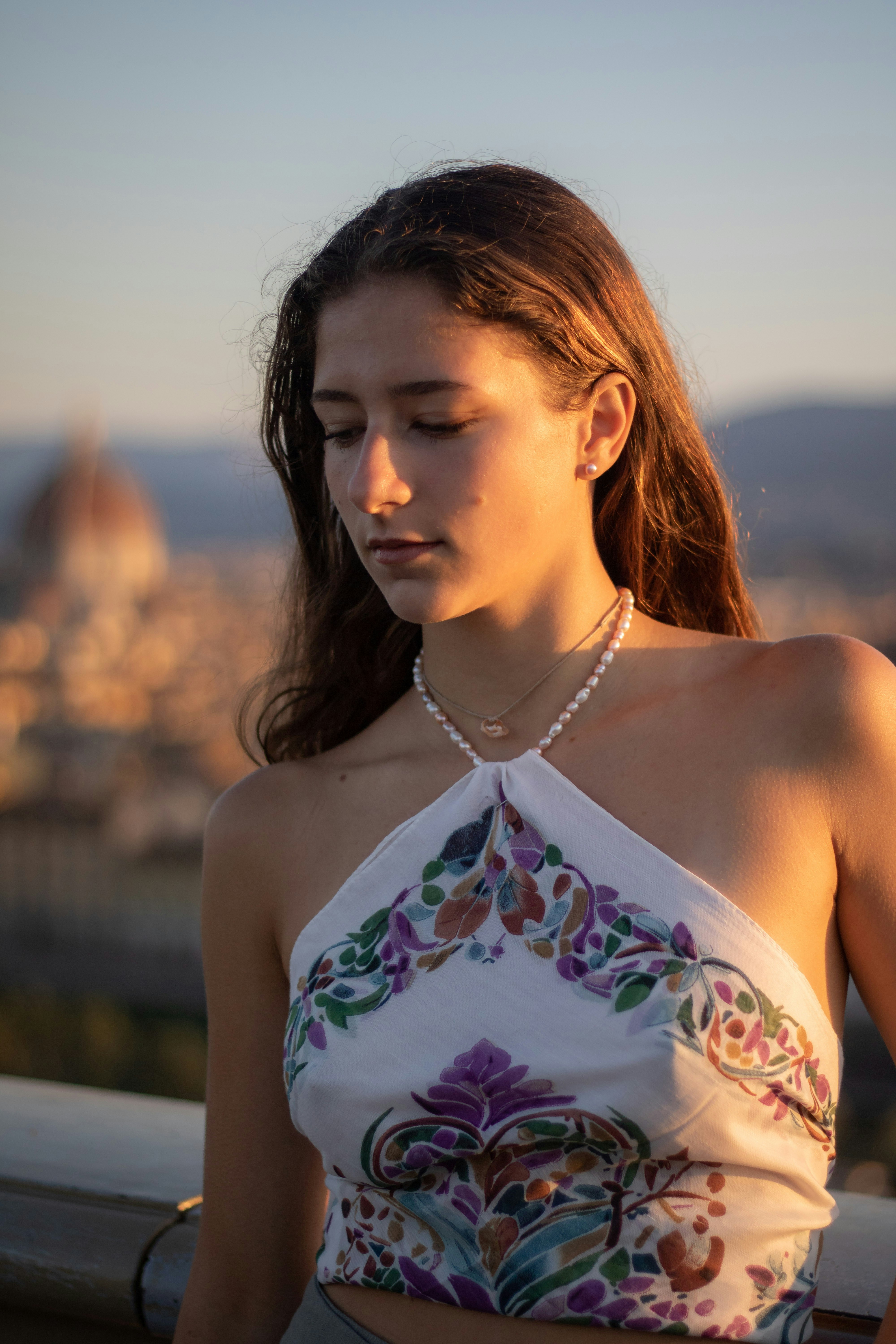 Young woman with long brown hair wearing a floral top.