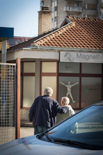 Two elderly men walk past a building with artwork