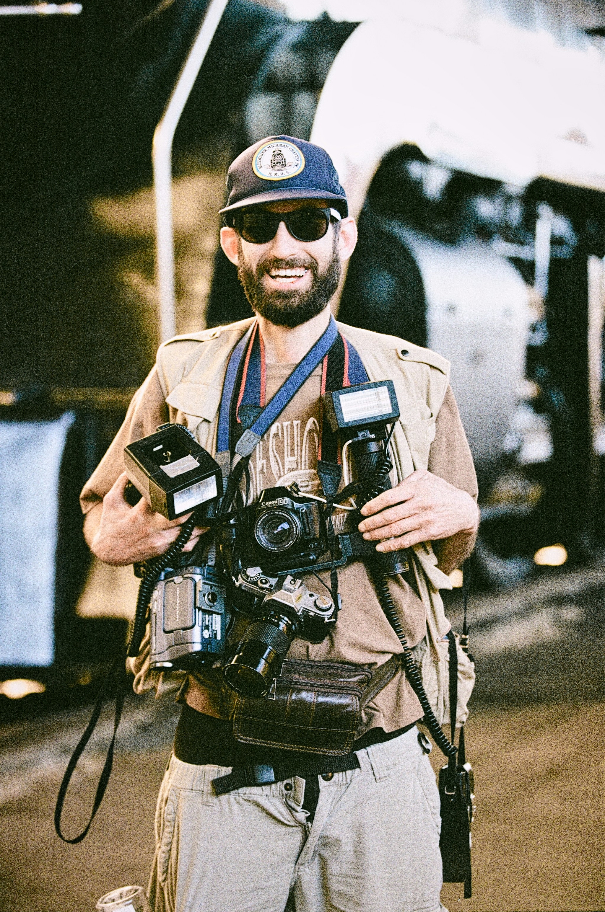 Man with cameras and equipment smiles