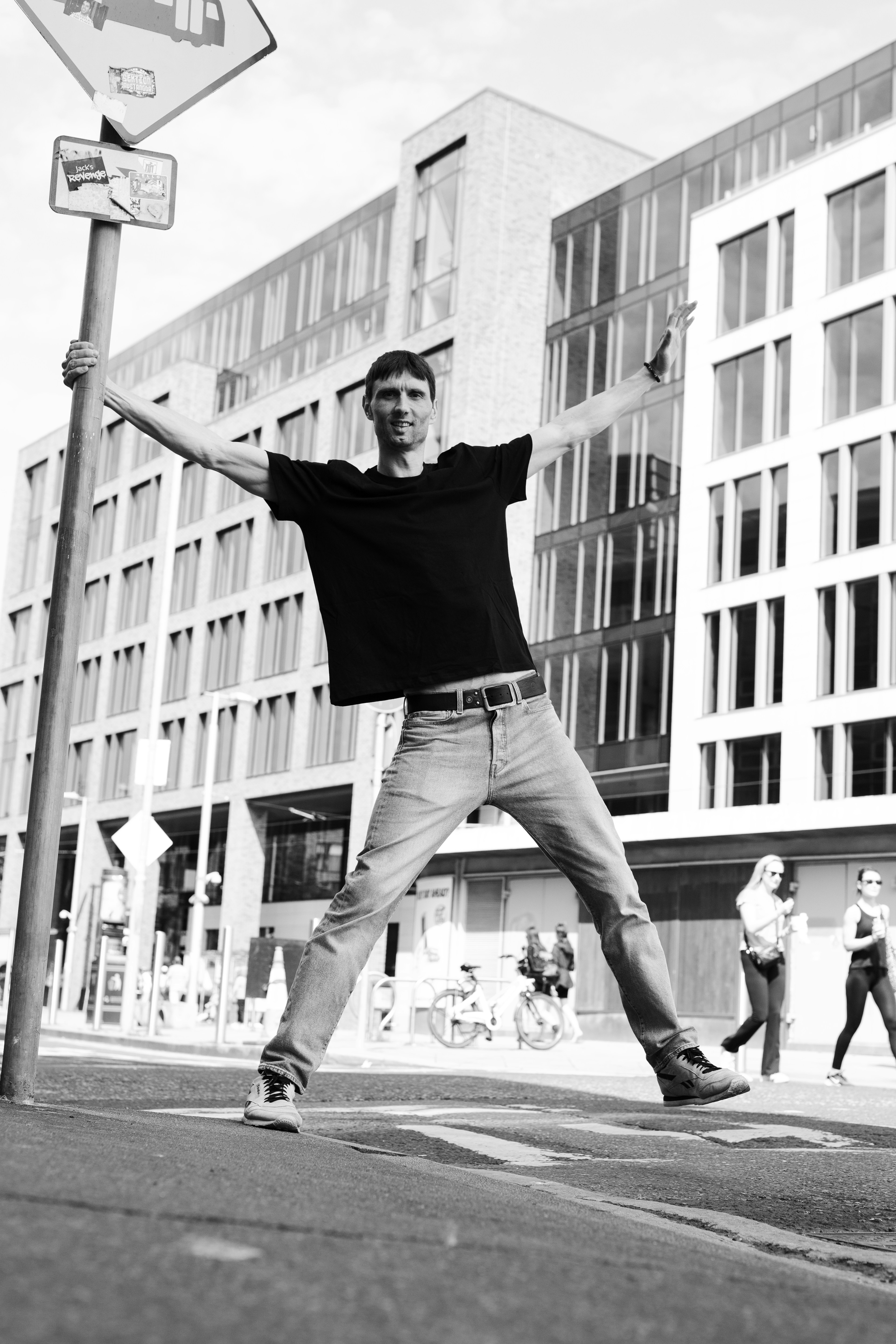 Man holding pole with arms outstretched on street