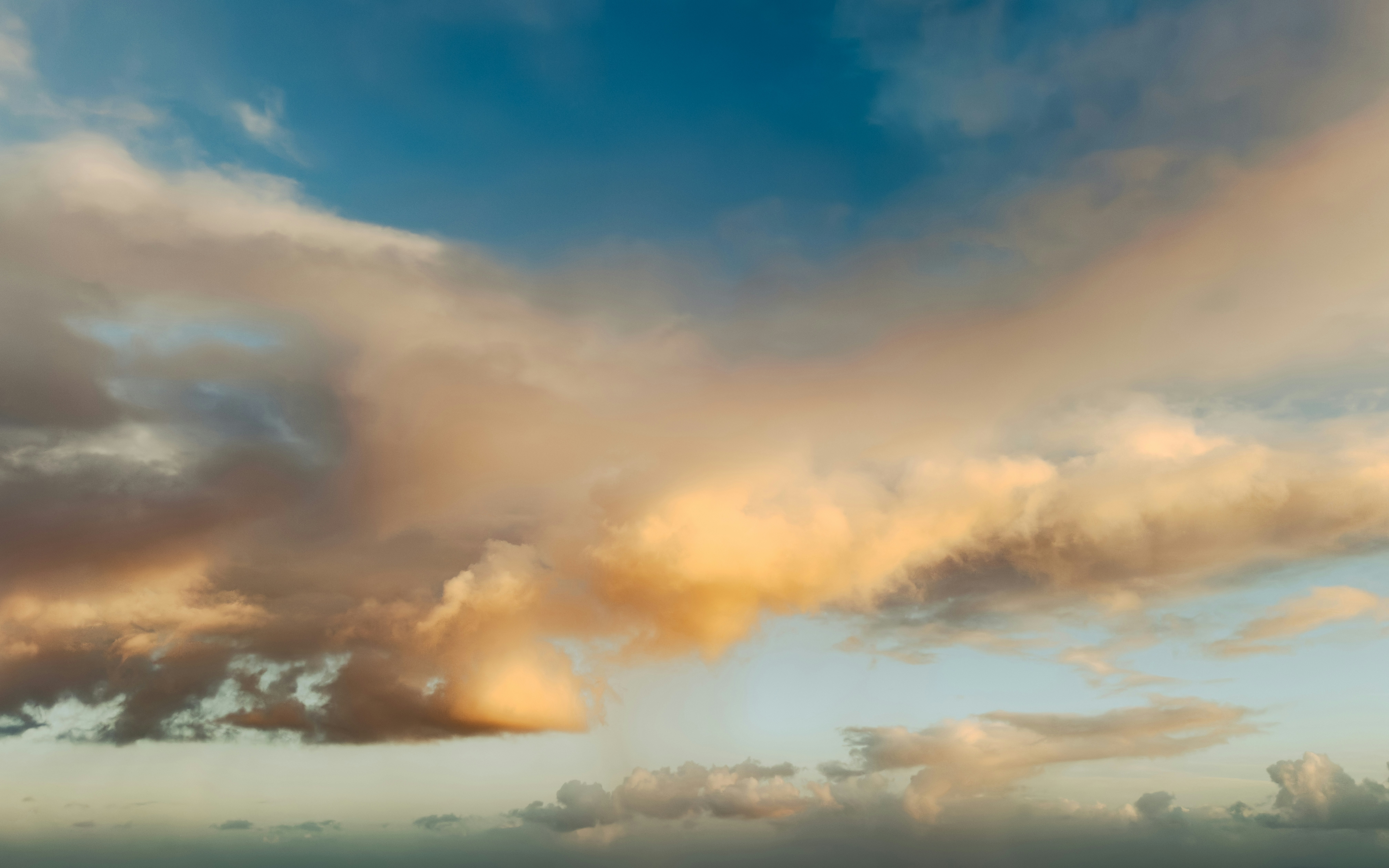 Goldene Wolken ziehen über einen blauen Himmel.
