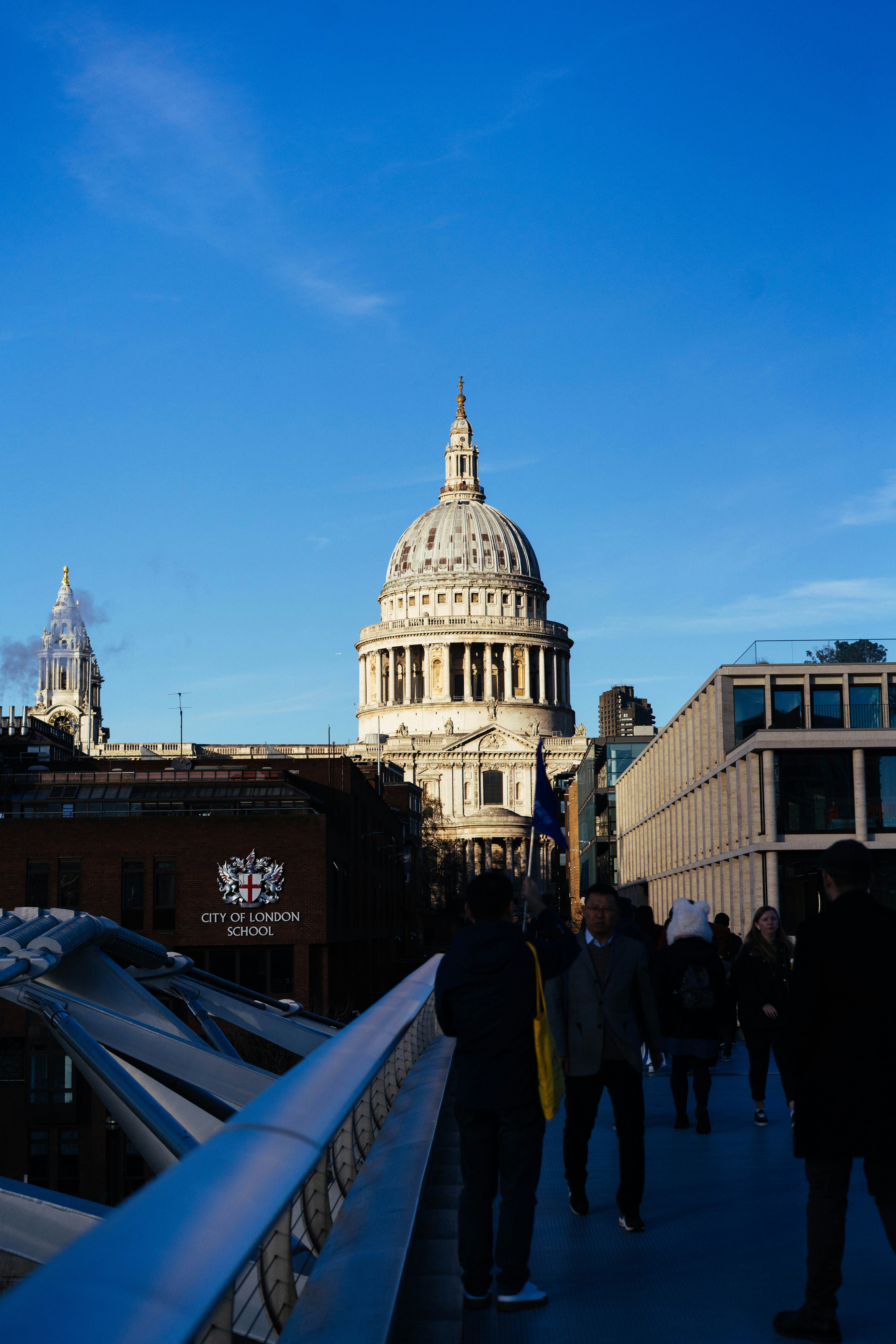People walking on a bridge towards st paul's cathedral.