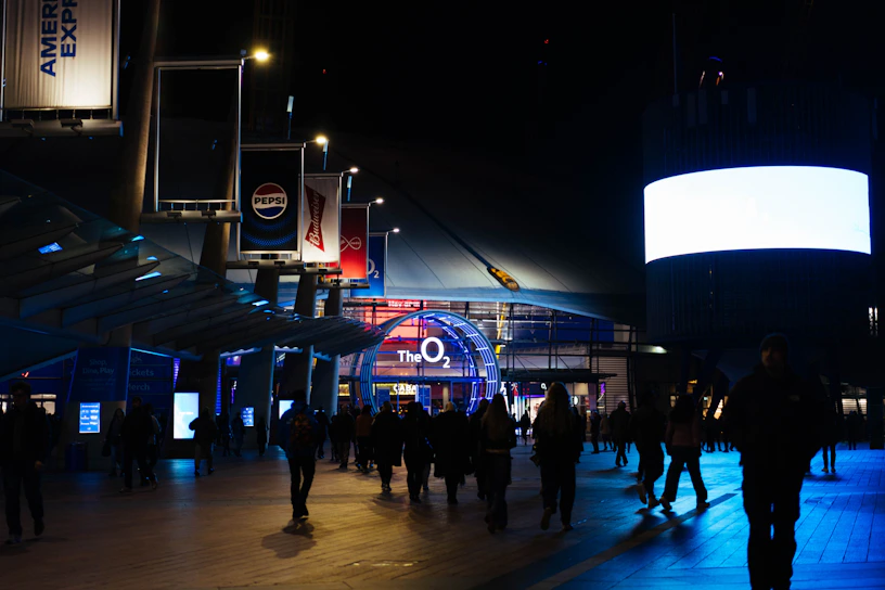 People walk around the o2 arena at night