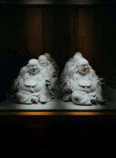 Several laughing buddha statues in dim light.