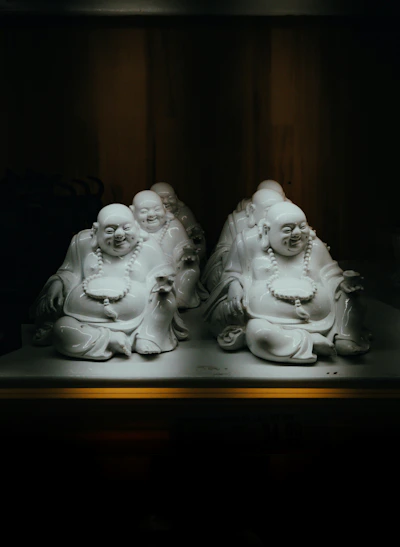 Several laughing buddha statues in dim light.
