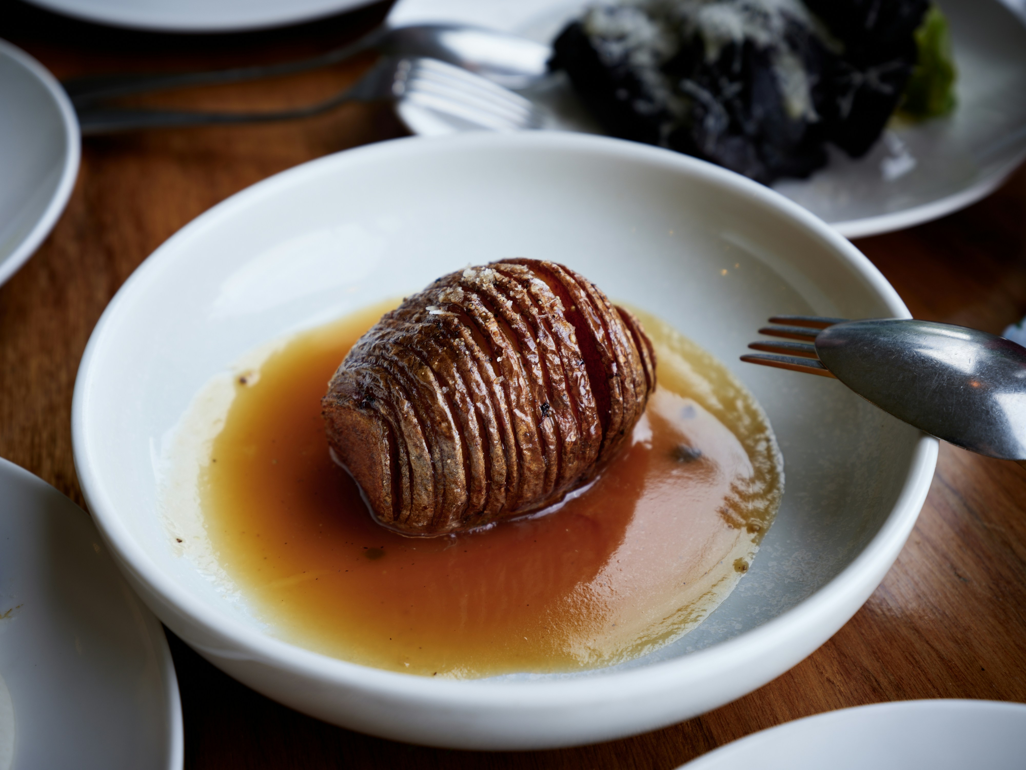 Hasselback potato served in a white bowl with sauce