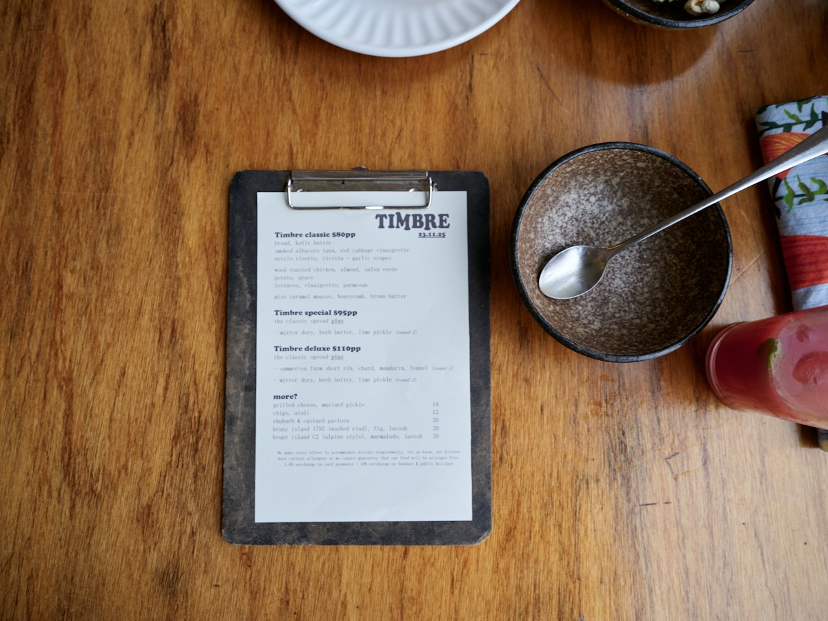 A wooden table with a menu listing food items, illustrating planning details for organizing service projects.