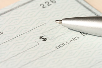 A pen rests on a check near the dollars line.