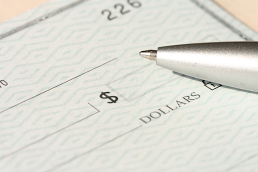 A pen rests on a check near the dollars line.