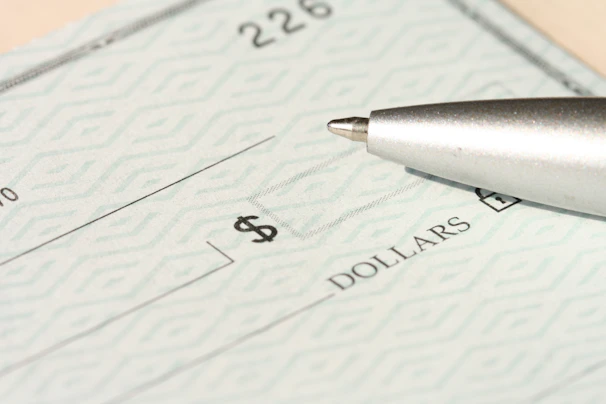 A pen rests on a check near the dollars line.