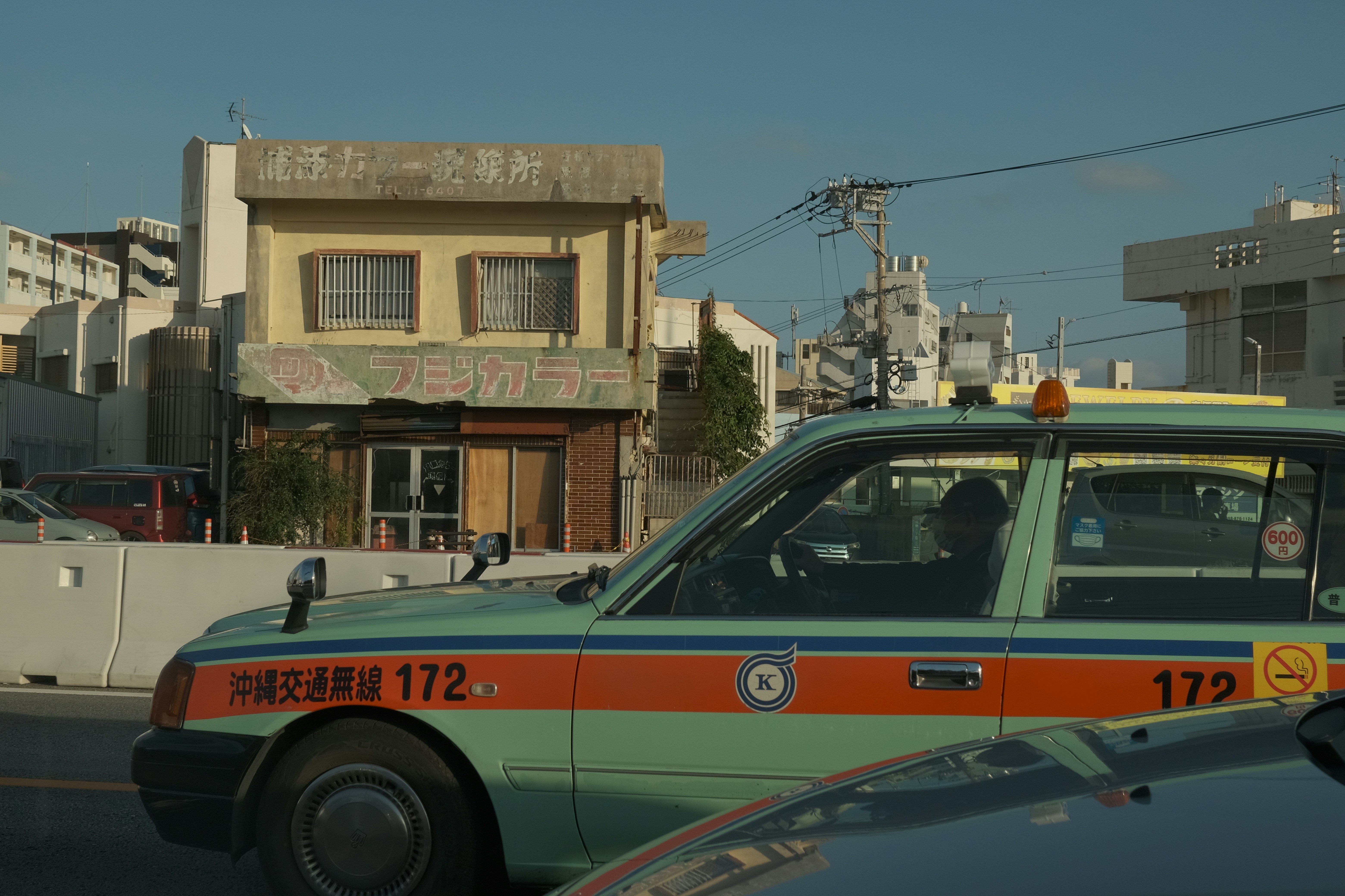 A green taxi with orange stripes drives on the road.