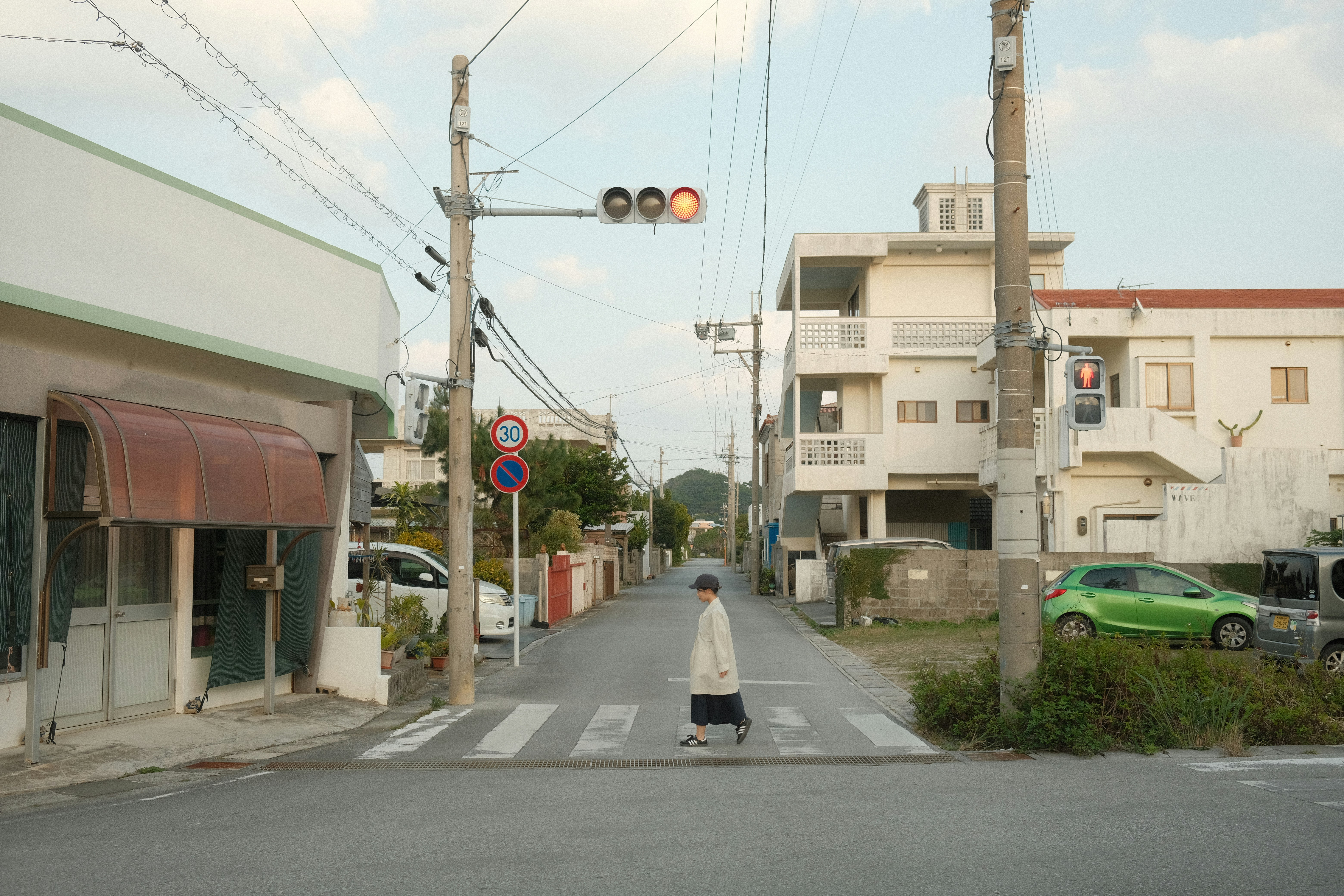 Person crossing a street in a quiet neighborhood.