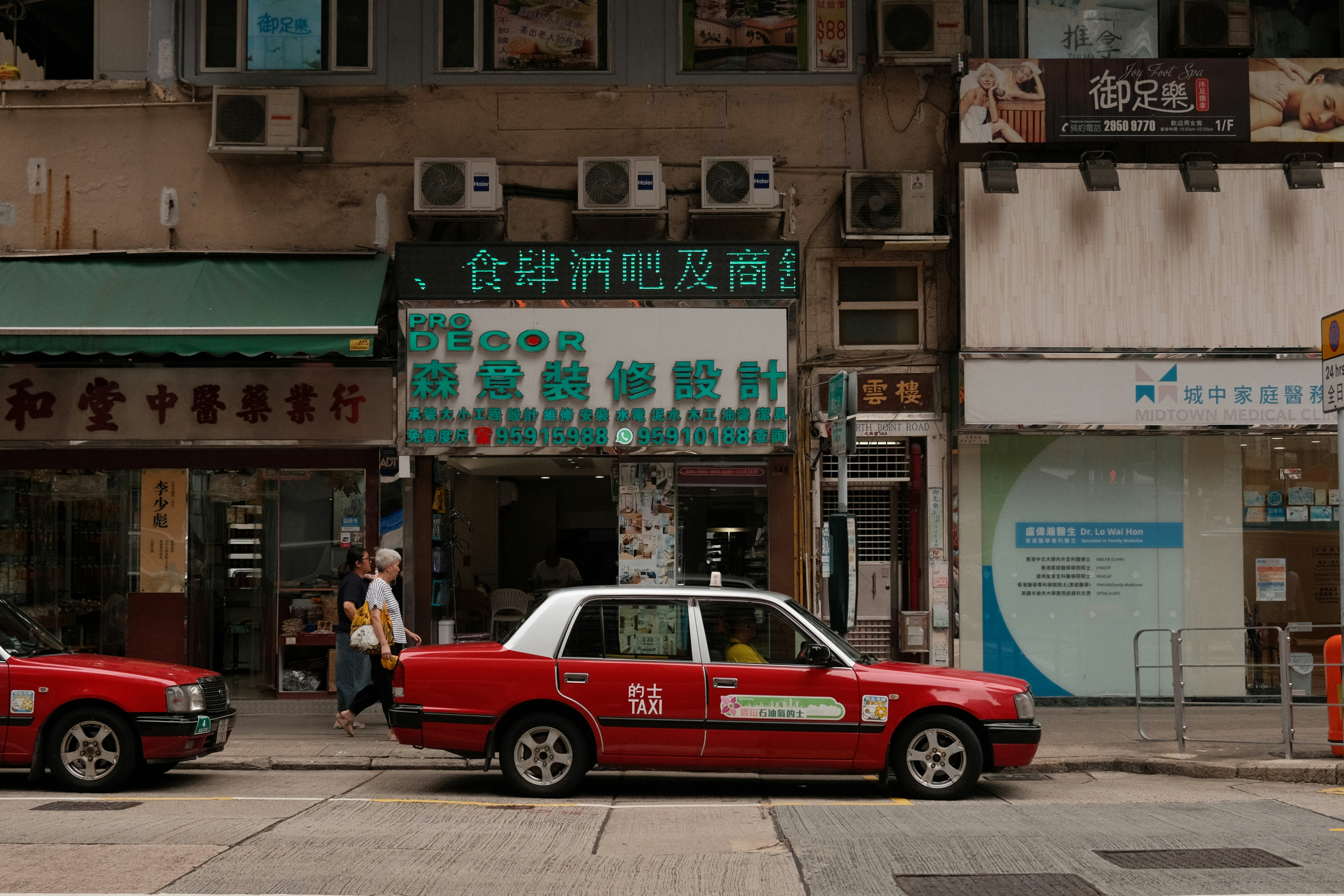 Red taxis on a city street with buildings.