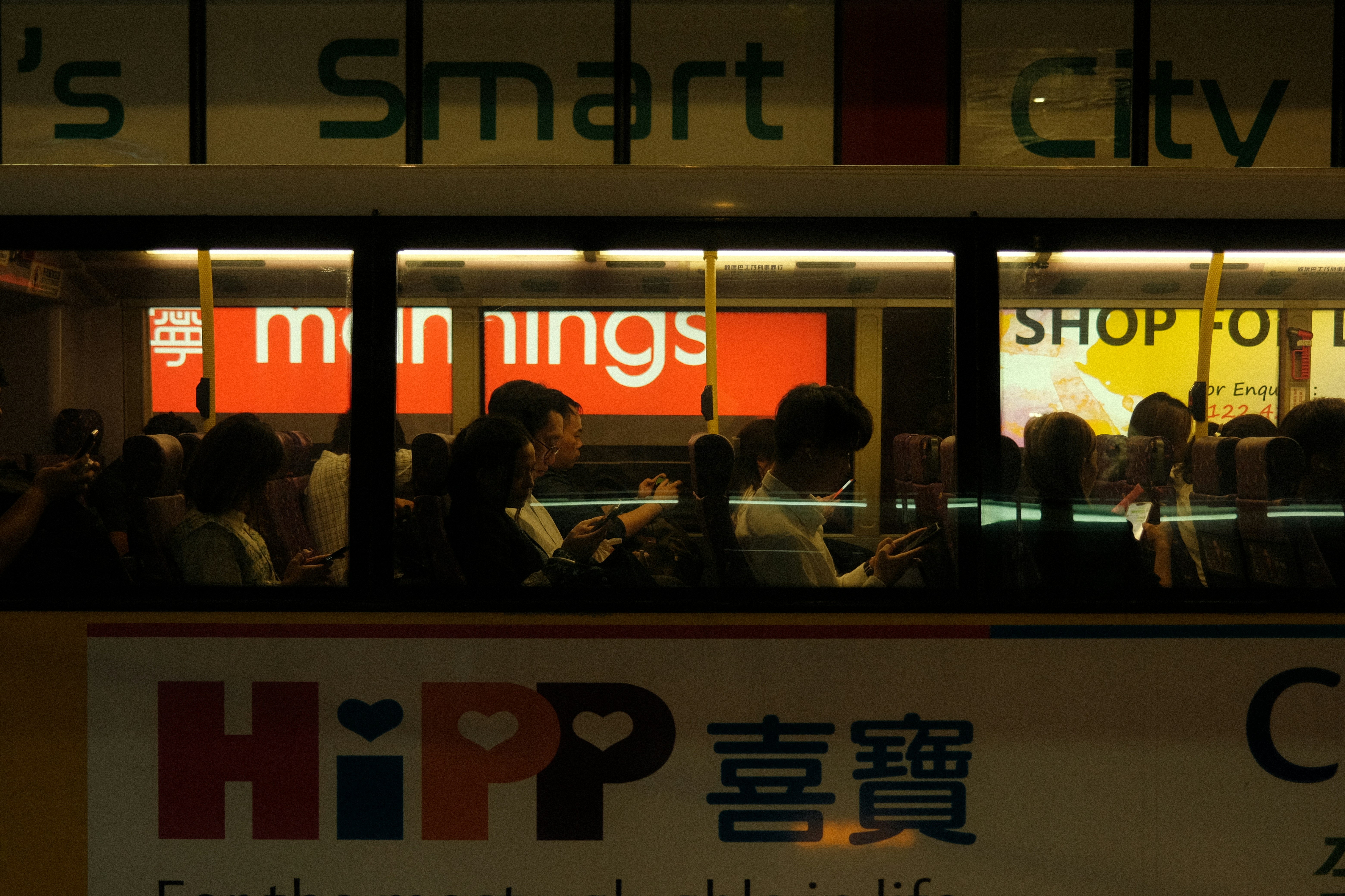 People inside a bus at night with city lights.