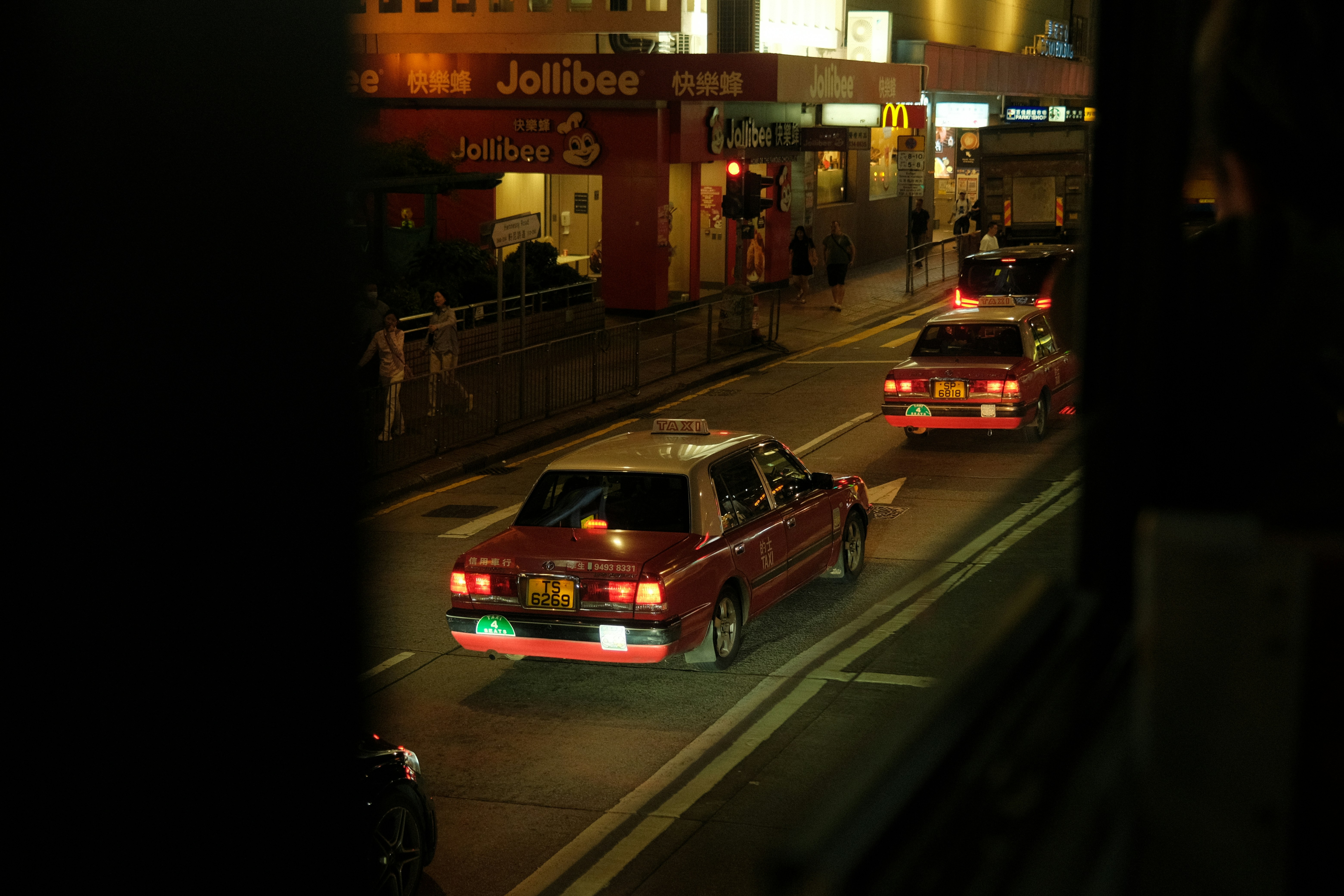 Red taxis drive down a city street at night.