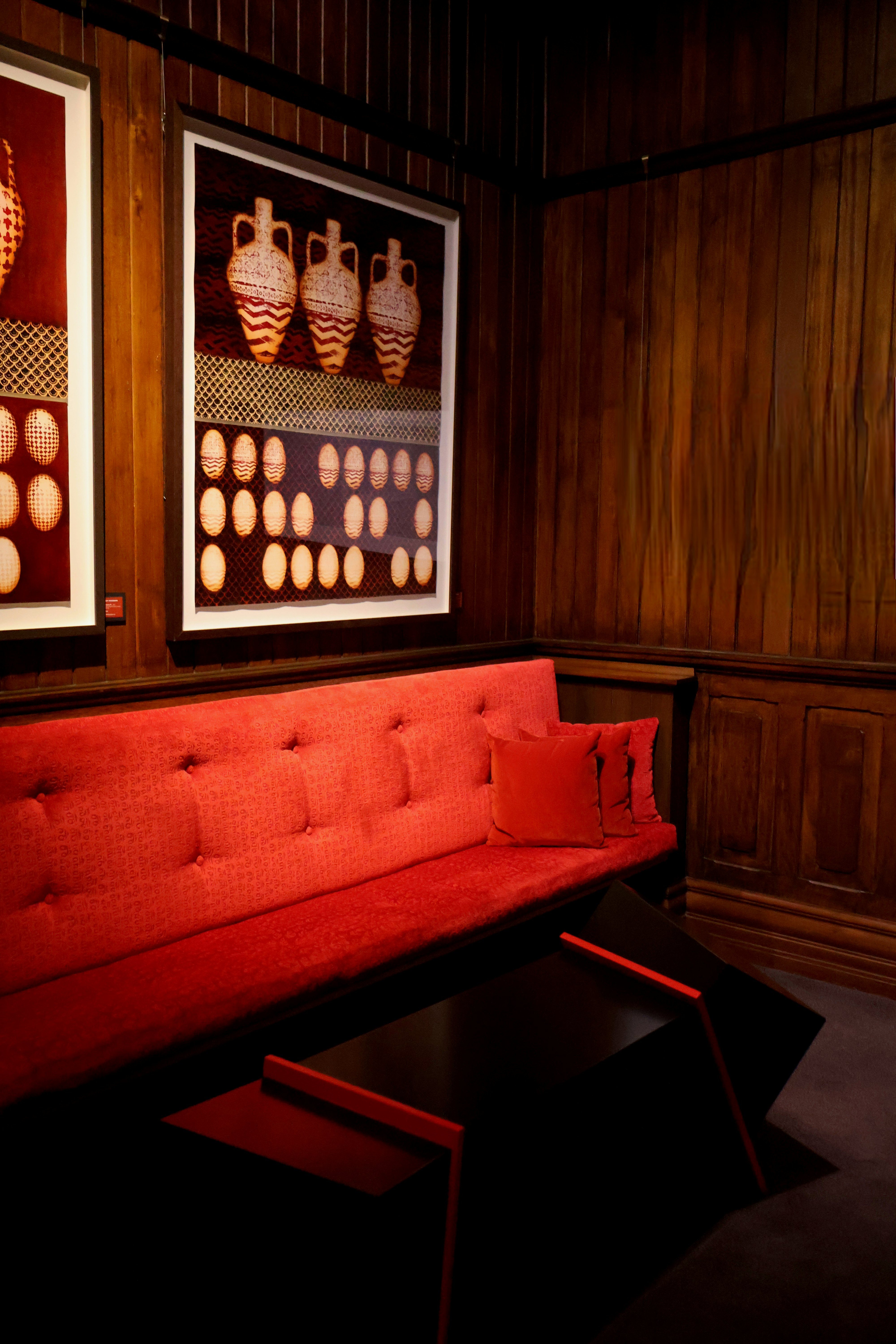 Red couch and art in a wood-paneled room