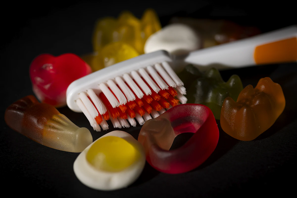 İllüstratif görsel: Gummy candies surround a toothbrush on black background