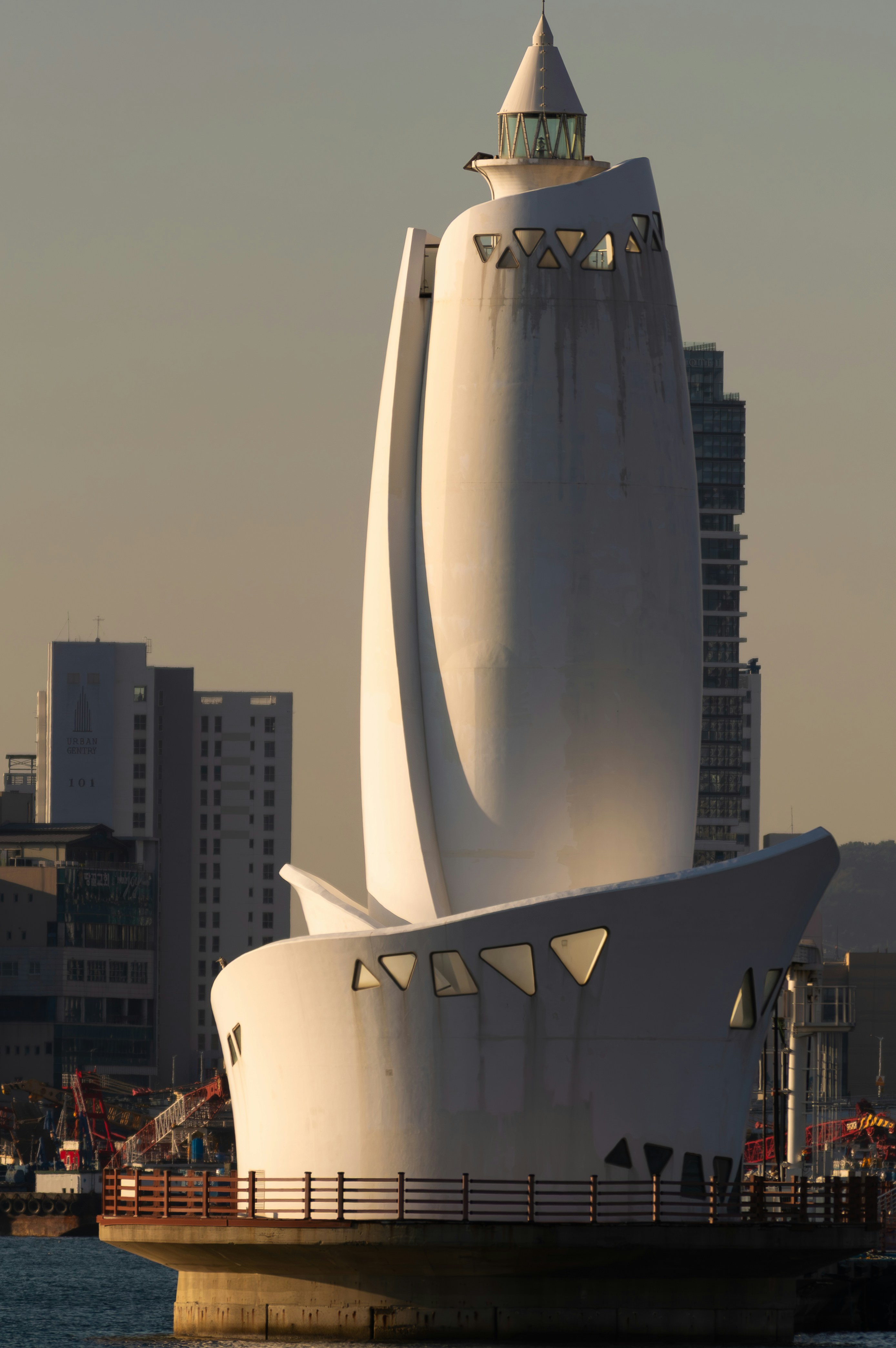 Faro blanco moderno con edificios urbanos al fondo