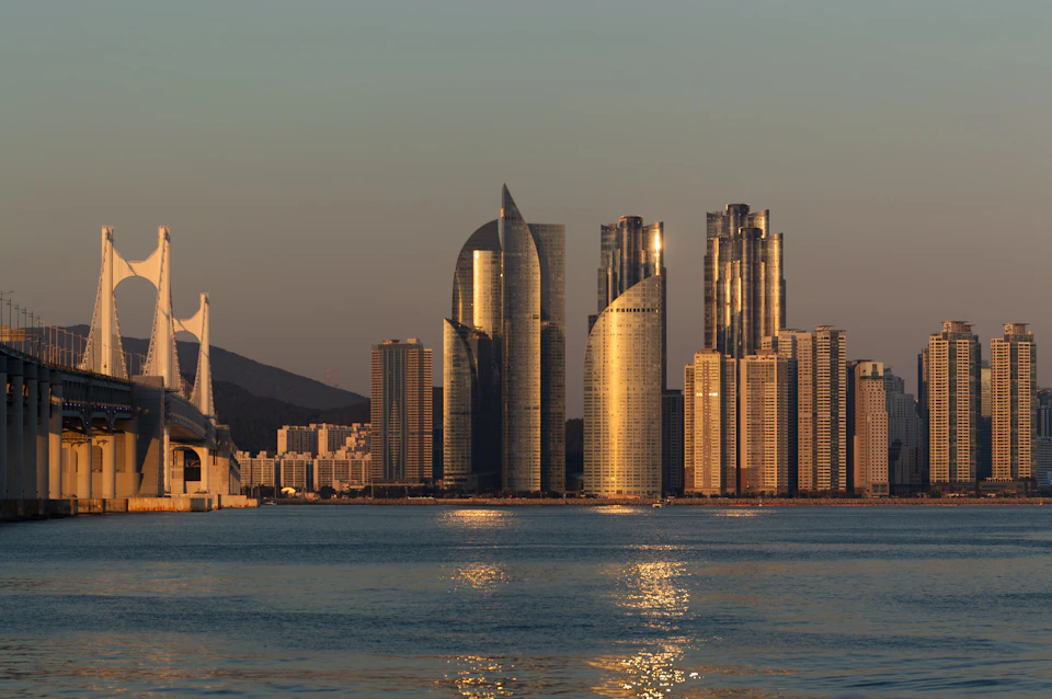 Seoul skyline with gray and white buildings against clear blue sky and prominent bridge
