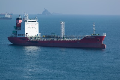 A large red tanker ship sails on the ocean.