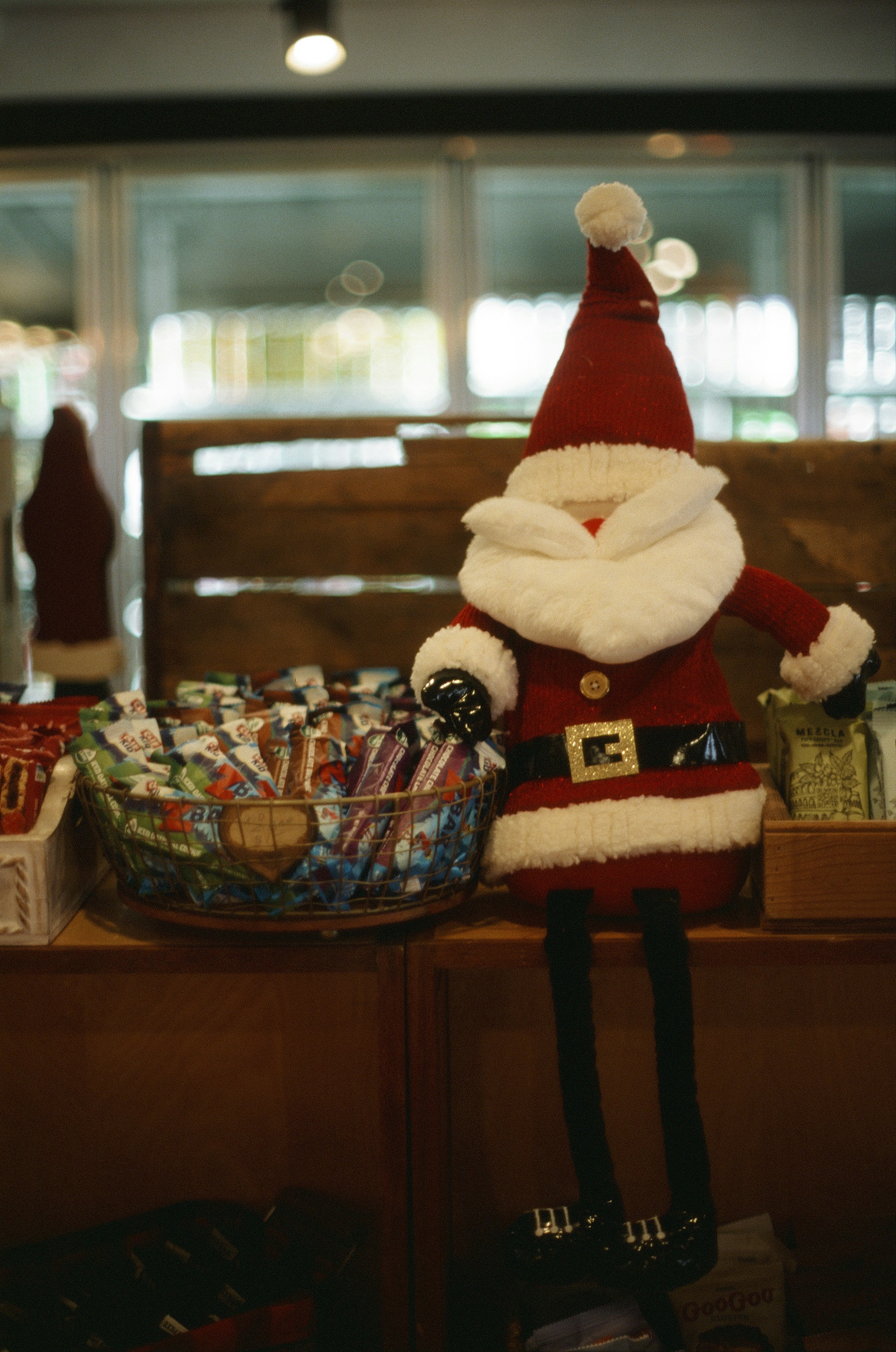 A santa claus doll sits next to candy canes.