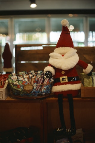 A santa claus doll sits next to candy canes.
