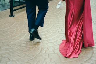 Couple walking in elegant attire on patterned floor.