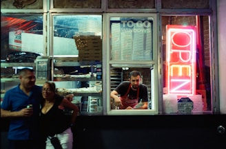 People order food at a brightly lit drive-thru window.