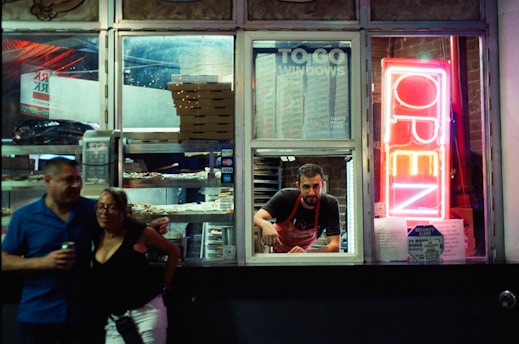 People order food at a brightly lit drive-thru window.