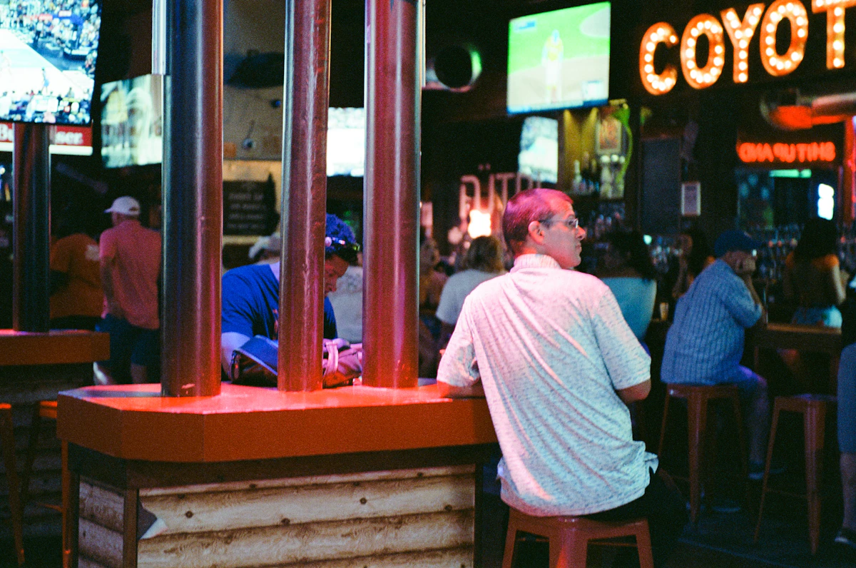 Des personnes assises à un bar avec des écrans montrant du sport en arrière-plan