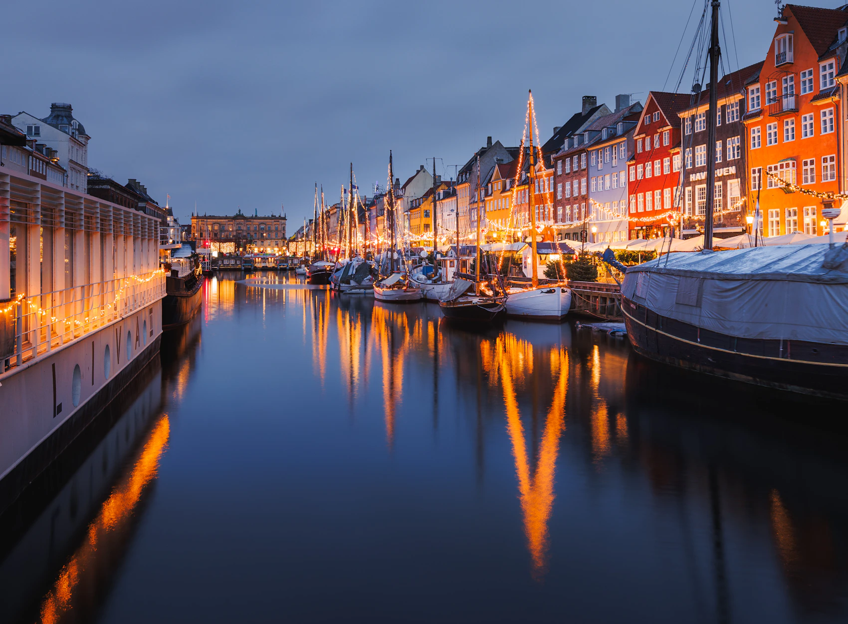 Nyhavn's historic houses, boats and warm lights reflected in the harbour at blue hour