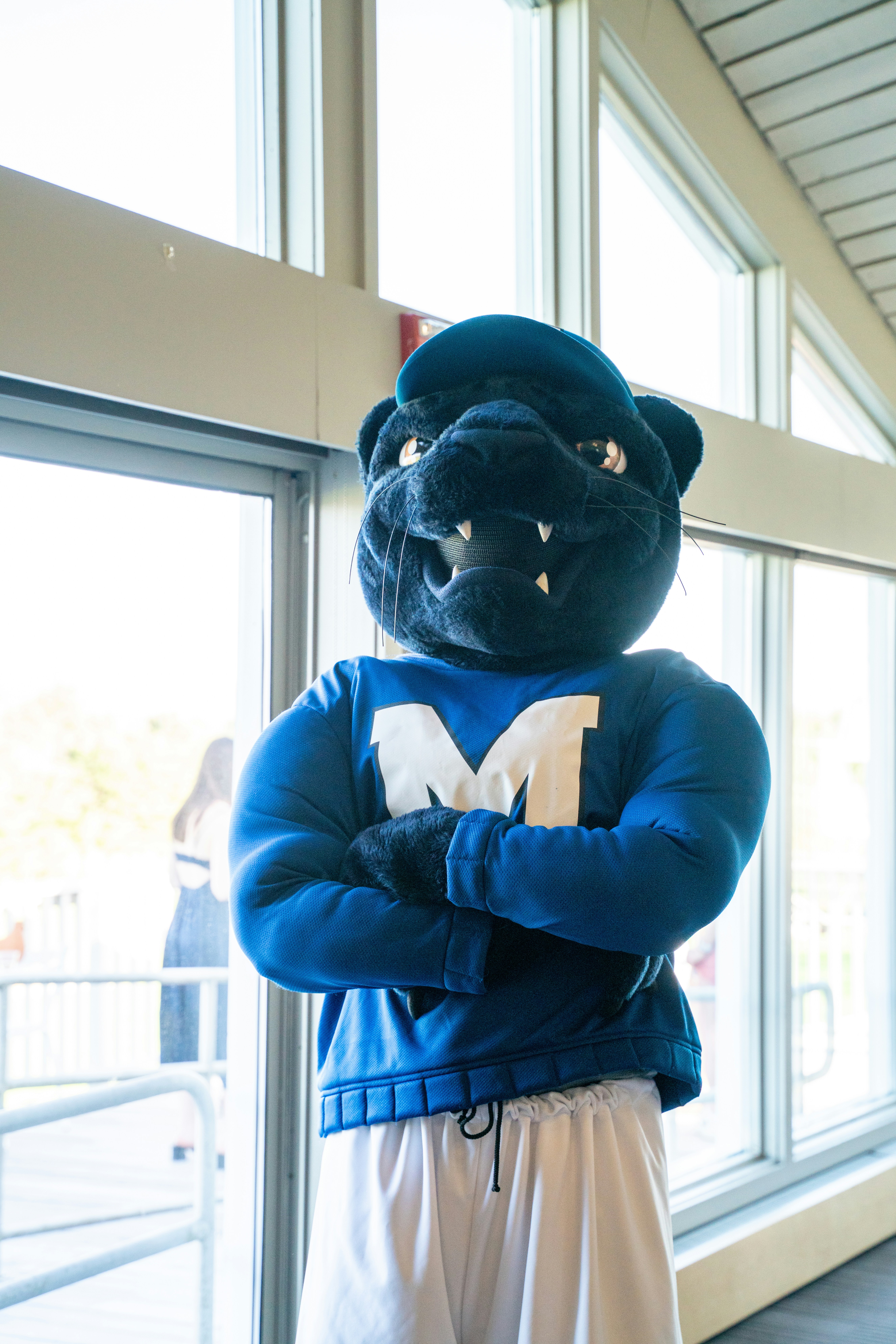 A person in a panther mascot costume with arms crossed