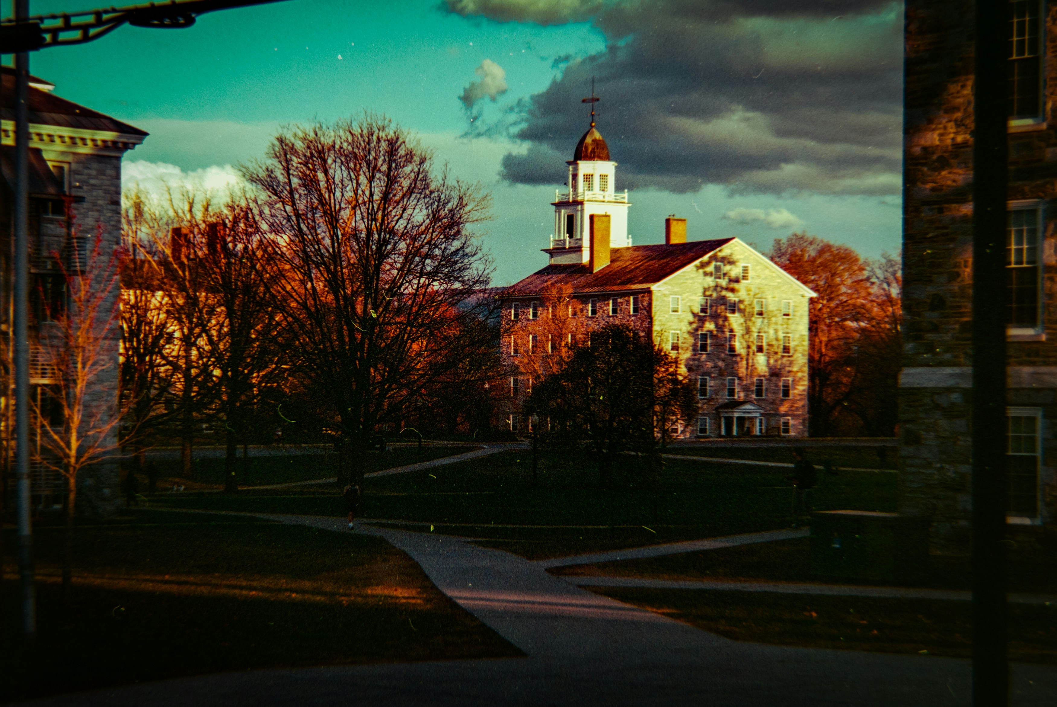 Historic building with autumn trees and dramatic clouds.