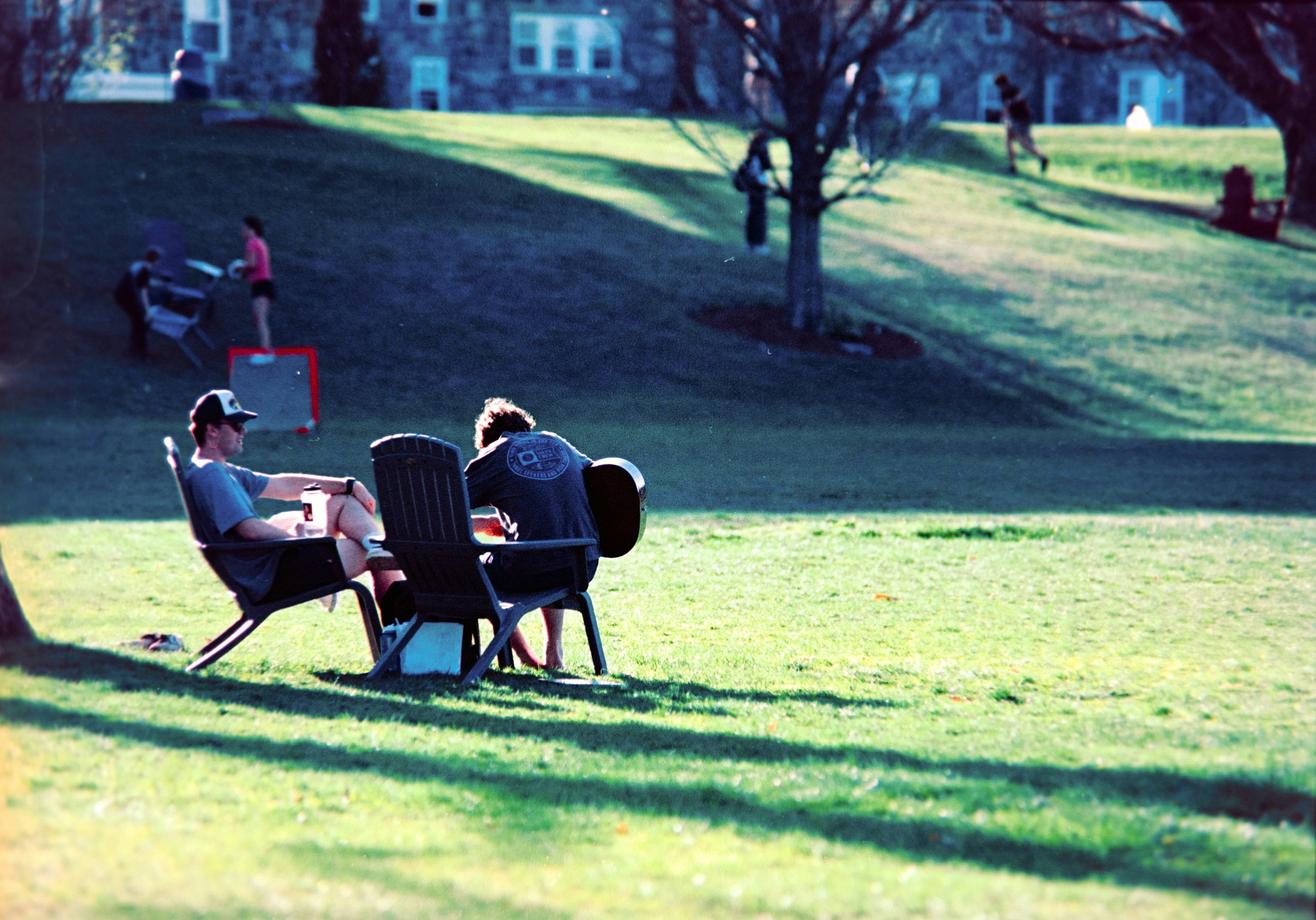 Zwei Menschen entspannen sich auf Stühlen in einem sonnigen Park.
