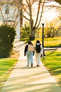 Two people walking on a path in a park.