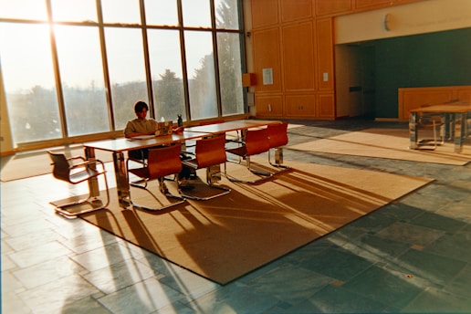 Man sitting at table with large windows and sunbeams.