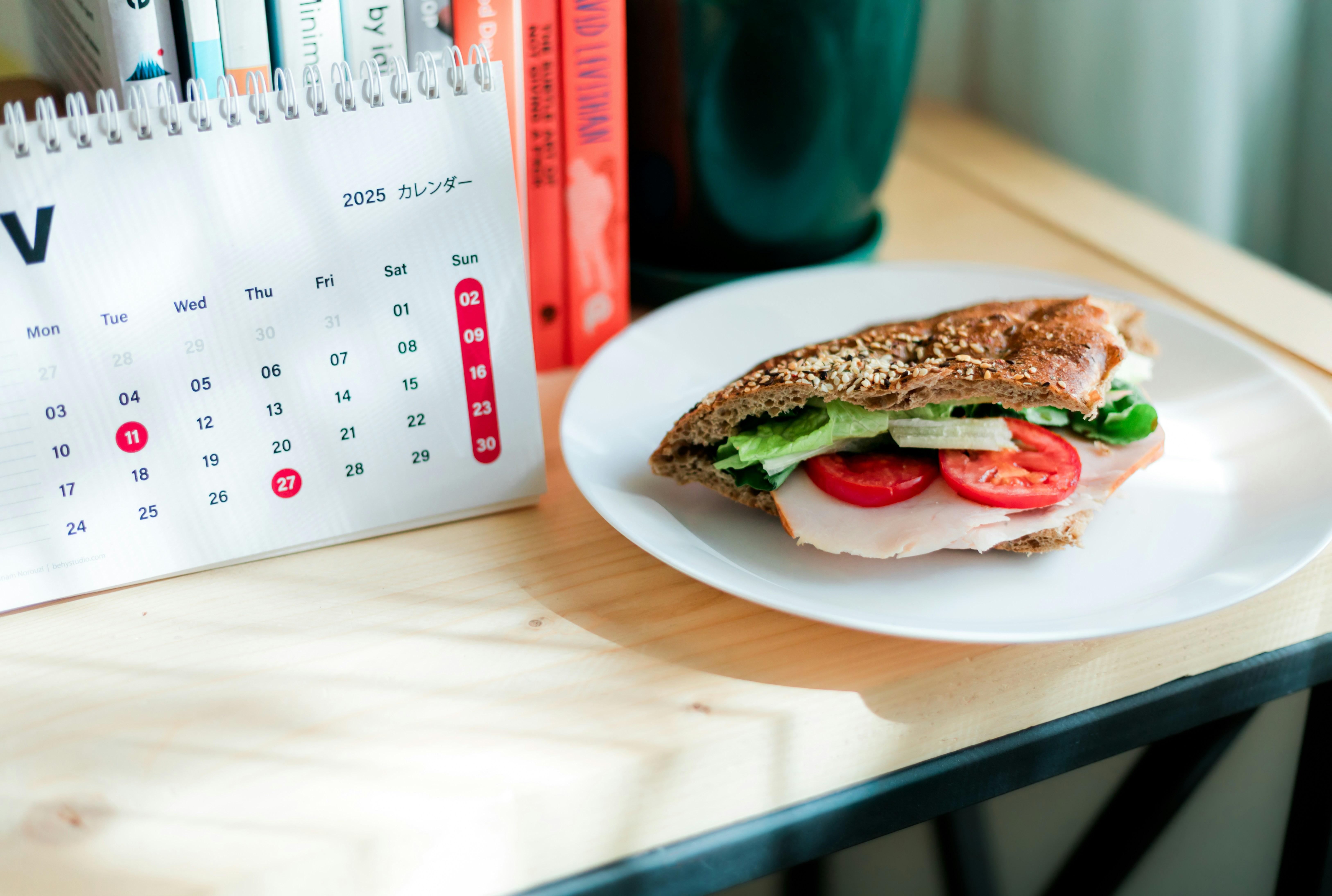 Sandwich with tomato and lettuce on a desk.