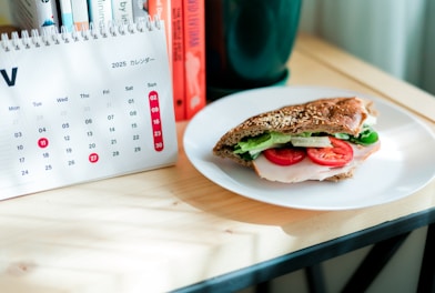 Sandwich with tomato and lettuce on a desk.
